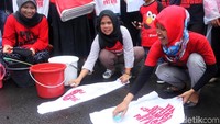 Dalam aksinya, mereka sempat mencuci baju di halaman kantor Kementerian Ketenagakerjaan.