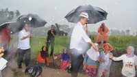Orang nomor satu di Indonesia itu turun dari mobilnya dengan payung hitam yang dipegangnya sendiri, ditemani Menteri PUPR Basuki Hadimuljono. Jokowi melangkah ke tengah sawah untuk mengecek proyek pembangunan irigasi. Dok. PUPR.