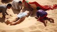 Traveler akan dikubur hidup-hidup, hanya menyisakan kepalanya saja. Kepala akan diganjal oleh handuk sebagai bantal, dan dinaungi selimut yang dibentuk seperti tenda mini. (Asmaa Waguih/Reuters)
