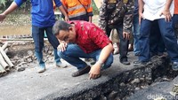 Anies tampak serius mengamati lokasi. Dia juga jongkok memeriksa retakan di jalan tersebut dan bertanya ke petugas.