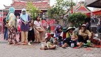 Para pemburu angpao berkumpul di luar pagar klenteng.