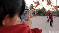 Pengunjung foto-foto dengan latar belakang pohon yang dihias lampion.