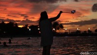 Seorang pengunjung asyik foto-foto di Pantai Ancol.