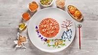 Yee sang ini juga bikin nggak tega dimakan. Lembaran salmon disusun di tengah dengan pelengkap edible flower dan lukisan bentuk anjing dan pohon sakura yang cantik. Foto: Istimewa