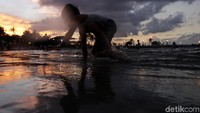 Seorang anak asyik bermain air dan pasir.