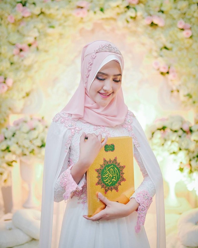 Lisya Nurrahmi memilih gaun putih bertabur payet merah muda dengan aksen cape dari bahan sifon. Ia pun menggunakan make up natural karya By Shantie. Foto: instagram.com/xhdrx