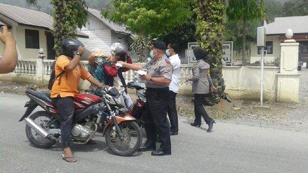Polisi membagikan masker kepada warga.