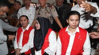 Anniesa memakai kerudung hitam saat menghadiri sidang perdana di PN Depok. Dia memadukannya dengan blus putih yang dilapis rompi tahanan oranye.