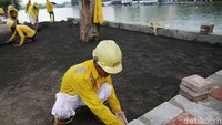 Seorang pekerja memasang konblok di sekitar danau.