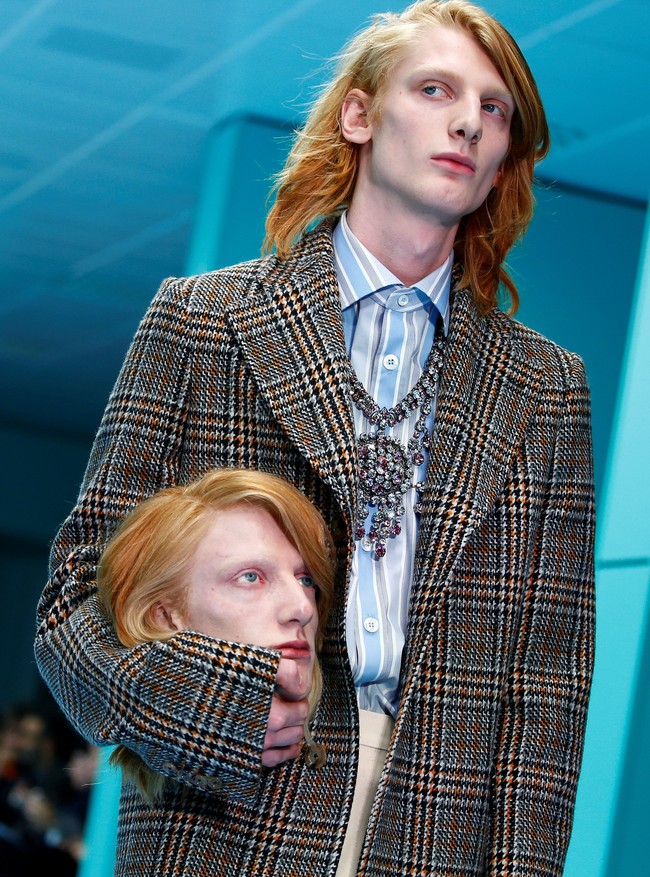 Lalu giliran model pria berambut merah dengan mantel motif kotak tampil, juga membawa kepala manusia yang wajahnya mirip dengannya. (Foto: REUTERS/Tony Gentile)