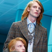 Lalu giliran model pria berambut merah dengan mantel motif kotak tampil, juga membawa kepala manusia yang wajahnya mirip dengannya. (Foto: REUTERS/Tony Gentile)