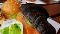 Kalau biasanya croissant berwarna cokelat, yang satu ini berwarna hitam. Croissant sandwich ini punya isian salmon asap, sayuran, dan mustard. Warna hitamnya menggugah selera! Foto: Instagram @hezicohen26 
