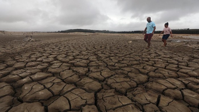 A family negotiates their way through caked mud around a dried up section of the Theewaterskloof dam near Cape Town, South Africa, January 20, 2018. The dam, which supplies most of Cape Towns potable water, is currently dangerously low as the city faces Day Zero, the point at which taps will be shut down accross the city. Picture taken January 20, 2018. REUTERS/Mike Hutchings
