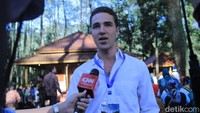 Gary tampil mengenakan kemeja putih, celana abu-abu dan menenteng satu kamera mirroless.