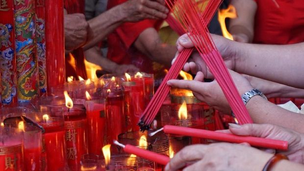 Menyalakan hio dan lilin untuk sembayang