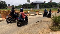 Di sisi kiri proyek, jalan umum warga tampak rusak. Banyak lubang-lubang mulai dari diameter besar hingga kecil.