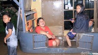 Sementara di rumah lain, sebuah keluarga juga bersantai di teras rumah mereka yang kebanjiran.