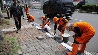 Beginilah aksi pasukan oranye mempercantik trotoar dengan mengecat kembali warna hitam dan putih yang sudah pudar.