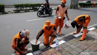 Petugas Penanganan Prasarana dan Sarana Umum (PPSU) alias Pasukan Oranye melakukan pengecatan trotoar di Jalan HR Rasuna Said, Jakarta.