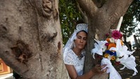 Seorang wanita memakai gaun pengantin dan membawa buket bunga. Dia memeluk pohon di San Jacinto Amilpas, Oaxaca, Meksiko.
