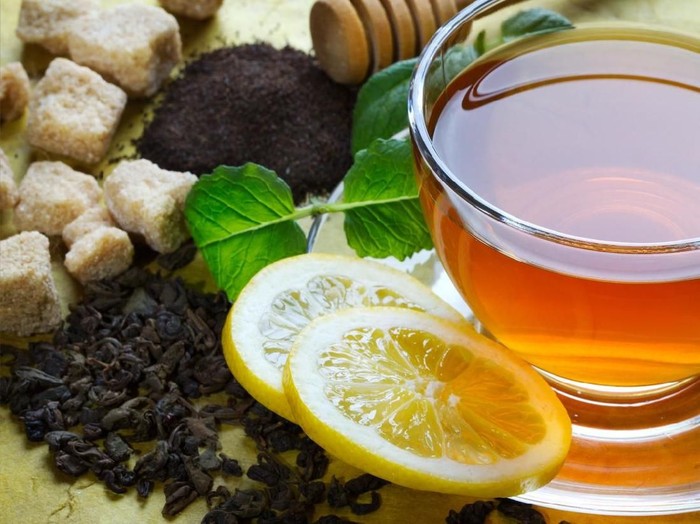 Cup of tea, mint leaves, lemon slices and brown sugar