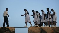 Foto: Di Srilanka, pelajar harus melewati papan di celah tembok Benteng Gelle. Mereka harus menyeberangi tembok yang berkuruan kecil dan sempit. (Vivek Prakash/Reuters)