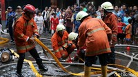 Petugas Damkar menyiapkan selang yang akan digunakan untuk menyemprotkan air ke titik api.