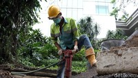 Pekerja membongkar trotoar yang akan dibangun.