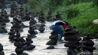 Sejumlah anggota kepolisian dan warga kemudian meminta Rahmat menunjukkan kepiawaiannya. Masih di sungai yang sama satu persatu batu dia susun hingga dalam satu menit satu susun batu selesai dia kerjakan. Foto: Syahdan Alamsyah