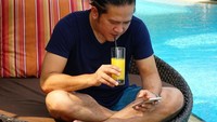 Jangan di dapur terus. Bolehlah sesekali menyeruput segelas orange juice di pinggir kolam renang. Tangan kanannya memegang gelas jus sementara tangan kirinya sibuk memainkan smartphone. Lagi update status ya Chef? Foto: Instagram