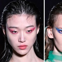 Makeup artist Pat McGrath membuat grafik eyeliner warna-warni di fashion show Prada. Uniknya, di atas eyeliner berwarnanya disematkan aksesori bling-bling.  Foto: Getty Images