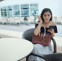 Duduk di restoran sambil melihat ponselnya, Angela Lee terlihat memangku tas Hermes Birkin berwarna merah marun yang pada bagian pegangan tasnya dihiasi scarf Hermes. Tas Hermes tersebut harganya diperkirakan Rp 250 jutaan. Foto: Instagram