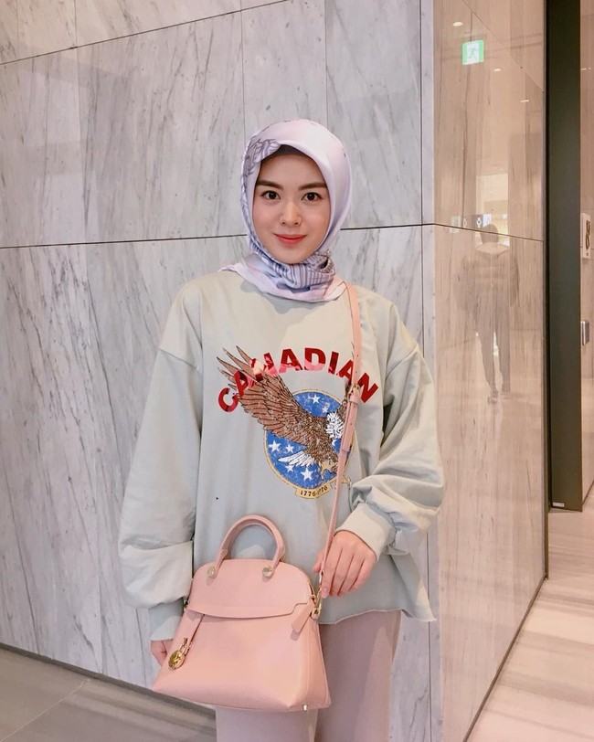 Ia pun kerap kali tampil kasual dengan hijab segi empat diikat kencang di bagian belakang. Bagi kamu yang suka gaya idol Korea, pemakaian oversized sweater ini bisa diikuti. Foto: Instagram Ayana Moon