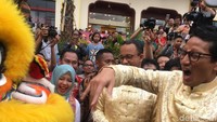 Sandiaga menunjukkan ekspresi kena gigit oleh barongsai itu, dengan memejamkan kedua matanya. Sementara istrinya, Nur Asia terlihat tertawa melihat ekspresi suaminya itu.