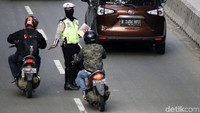 Polisi menyetop pengendara sepeda motor yang menerobos jalur cepat.