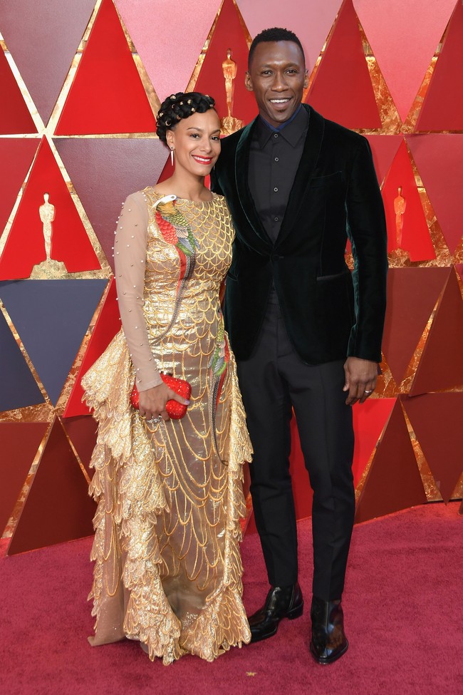Istri Mahershala Ali, Amatus Sami-Karim memakai busana metalik dengan dua gambar burung beo di tubuhnya. Tapi jika dilihat sekilas, teksur gaunnya lebih mirip sirip ikan dibanding bulu burung beo. Foto: Getty Images