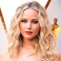 Ingin tampil lebih glamour namun tidak berlebihan? Gaya Jennifer Lawrence dengan lipstik oranye dan eyeshadow hitam yang dibuat cat-eye ini bisa ditiru. Foto: Getty Images