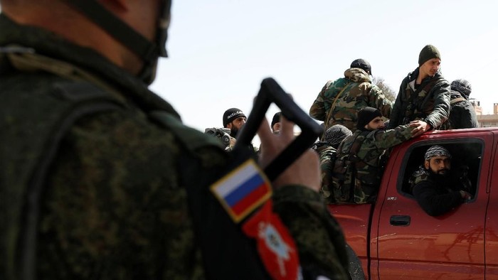 A Russian soldier gestures to Syrian soldiers at a checkpoint near Wafideen camp in Damascus, Syria March 2, 2018.REUTERS/Omar Sanadiki