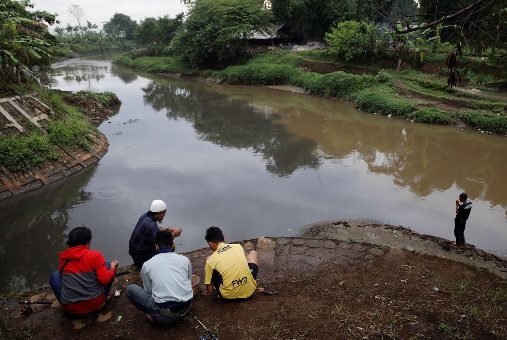 Men fish at a polluted tributary, which runs through an area densely populated with textile factories and where it joins the Citarum river, near Majalaya, south-east of Bandung, West Java province, Indonesia, February 14, 2018. REUTERS/Darren Whiteside  SEARCH 