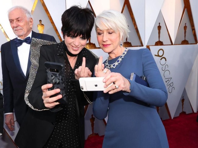 Usia boleh senja, tapi Diane Warren dan Helen Mirren tetap punya jiwa anak muda. Mereka berpose selfie sambil mengacungkan jari tengah. Tapi pose ini sebaiknya jangan ditiru ya, guys! Foto: Getty Images