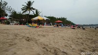 Tenda-tenda payung yang berjajar rapih di pinggir pantai biasanya jadi pilihan wisawatan asing untuk berjemur sekaligus melihat sunset. Tapi tak sedikit pula yang memilih pasir pantai sebagai alas duduk (Bonauli/detikTravel)