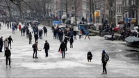 Warga Amsterdam harus mengalami musim dingin yang lumayan buruk. Sungai-sungai di sana sampai membeku. Tapi oleh warga sekitar, sungai ini malah dipakai buat main ice skating. (Michael Kooren/Reuters)