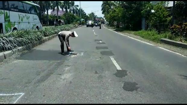 Polisi memberi tanda cat putih pada jalan yang rusak