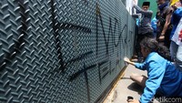 Seorang mahasiswa menulisi pagar DPR dengan pilok.