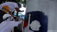 Proses pembuatan mural di salah satu tiang.
