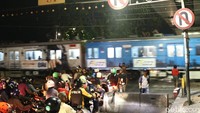 Warga mengatur lalu-lintas saat kereta commuter line melintas di perlintasan tersebut.