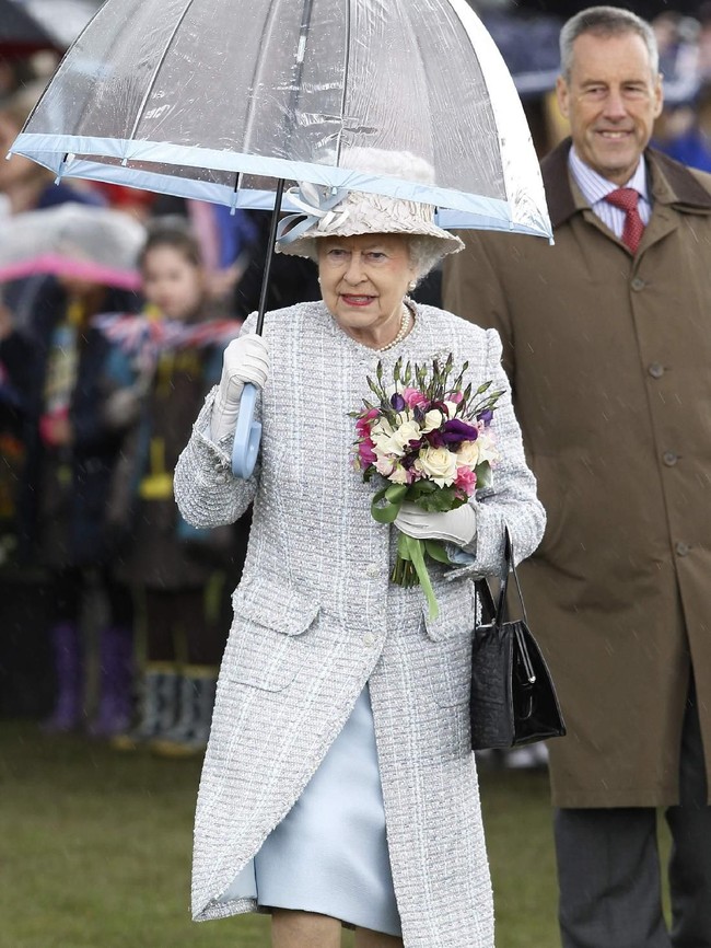 Ratu Elizabeth II berbalut busana biru muda dengan payung berwarna senada saat berkunjung ke Richmond, Inggris.  Foto: dok: Getty Images