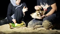 Ini saat Rina berada di Bali. Duh, ternyata begini ya kalau makan nasi padang bungkus beralaskan pasir pantai. Jangan sampai pasirnya ikut kemakan, ya!  Foto: Instagram @rinanose16