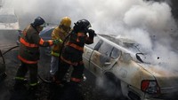 Para petugas damkar itu asling bahu-membahu menggotong selang dan menyemprotkan air ke mobil-mobil sitaan polisi yang kebakaran.