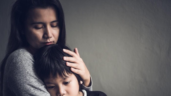 Sad little boy being hugged by his mother at home. Parenthood, Love and togetherness concept.
